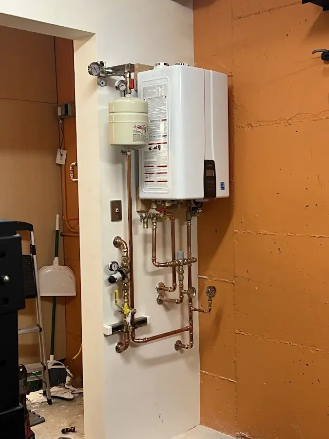 Plumbing technician inspecting water heater connections in White Deer